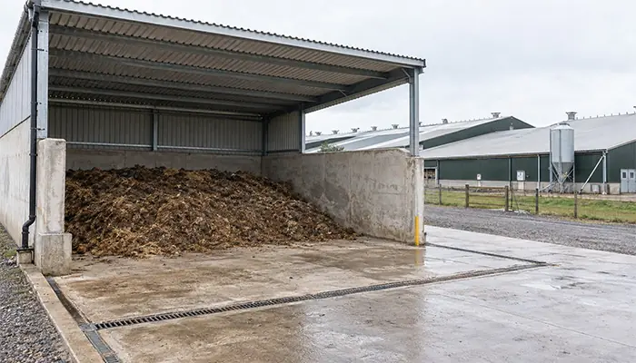 Covered poultry manure storage bay with concrete retaining walls and a contained collection area.