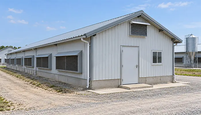 A detached farm brooder house with a weatherproof roof, closed service door and ventilation openings